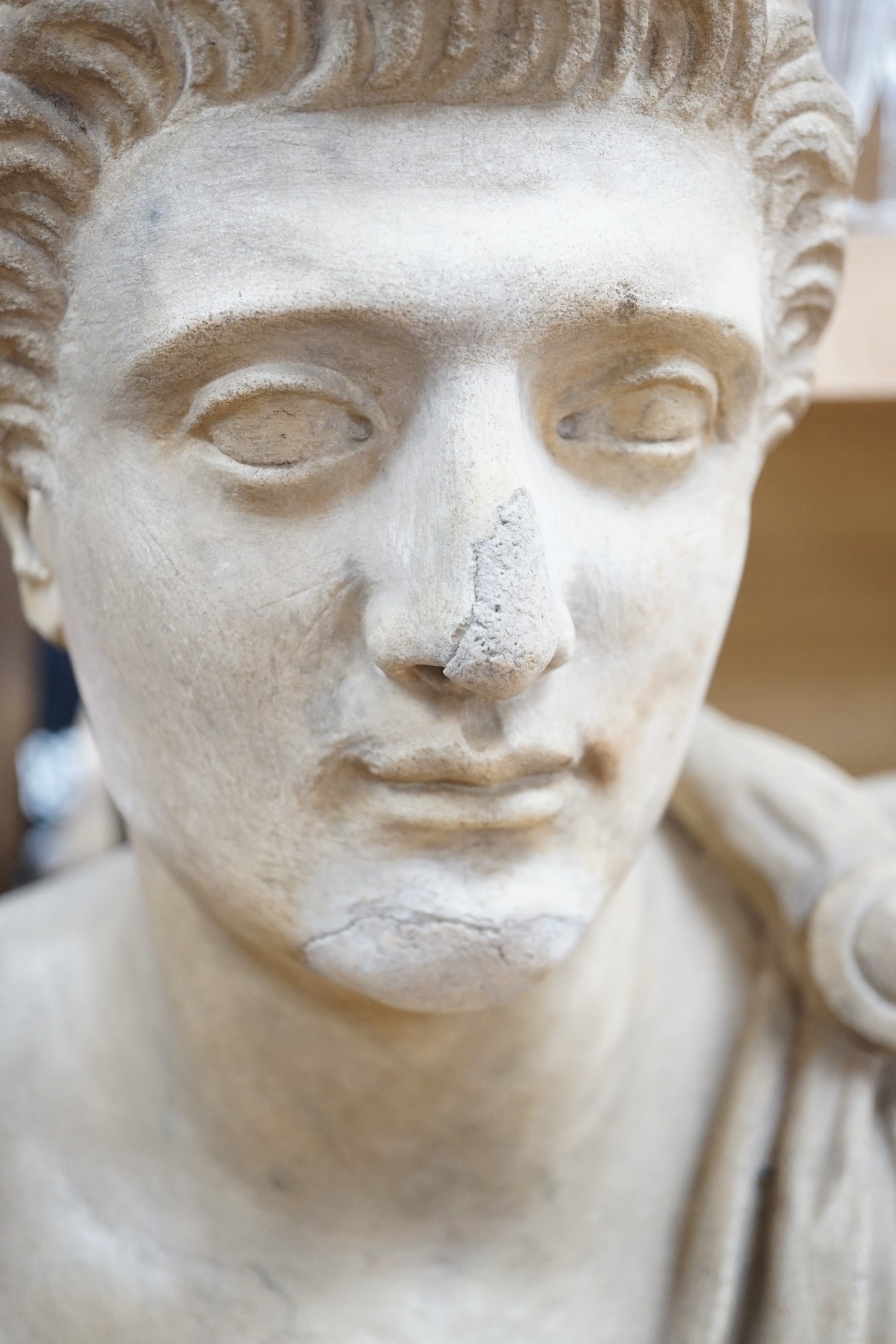 After the Antique marble bust of a Roman man wearing a Chlamys with a buckle at the shoulder, later socle and repairs, 54cm tall